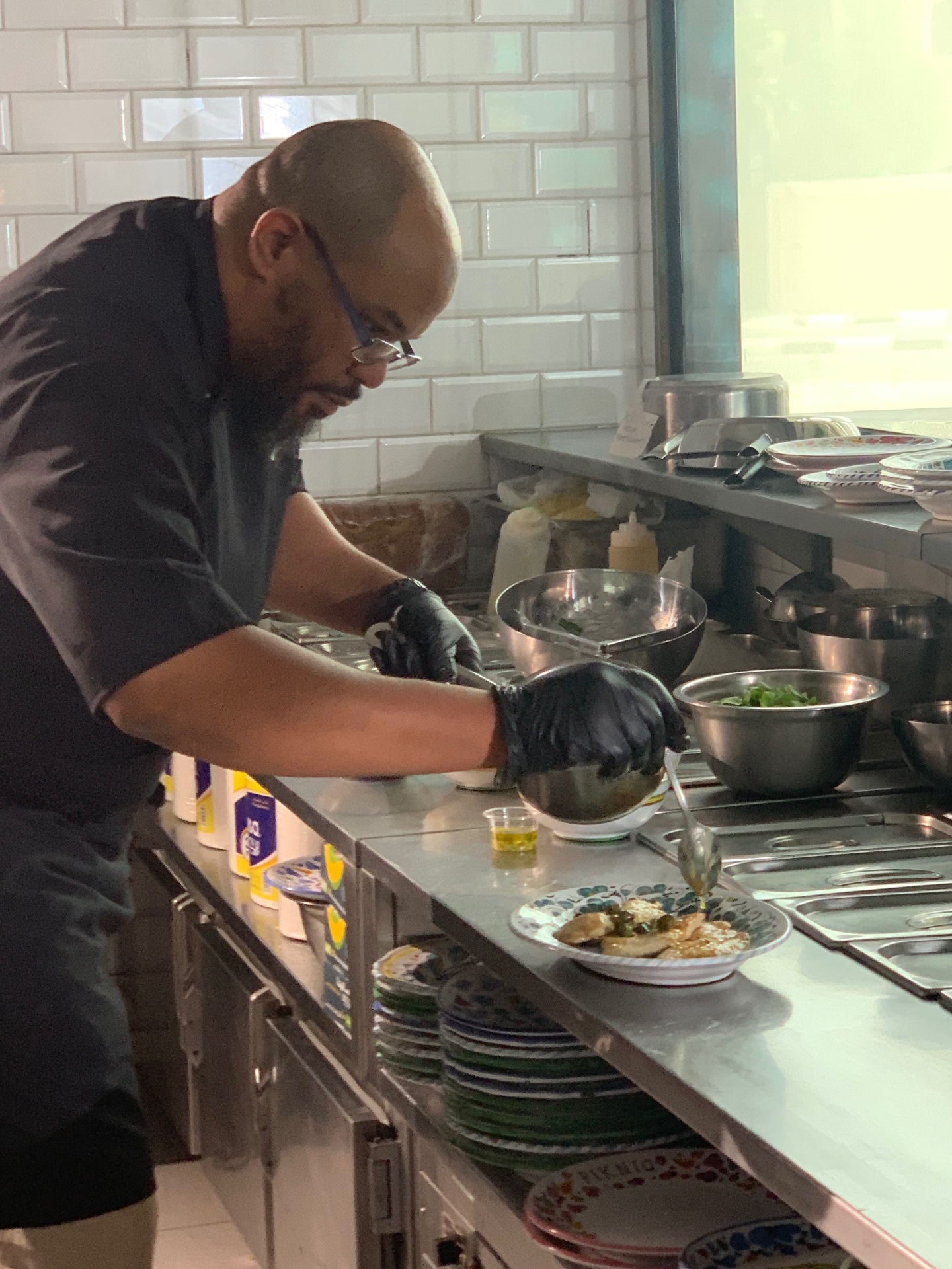 Chef Ahmed nappant une assiette à la cuillère lors du dressage en cuisine professionnelle