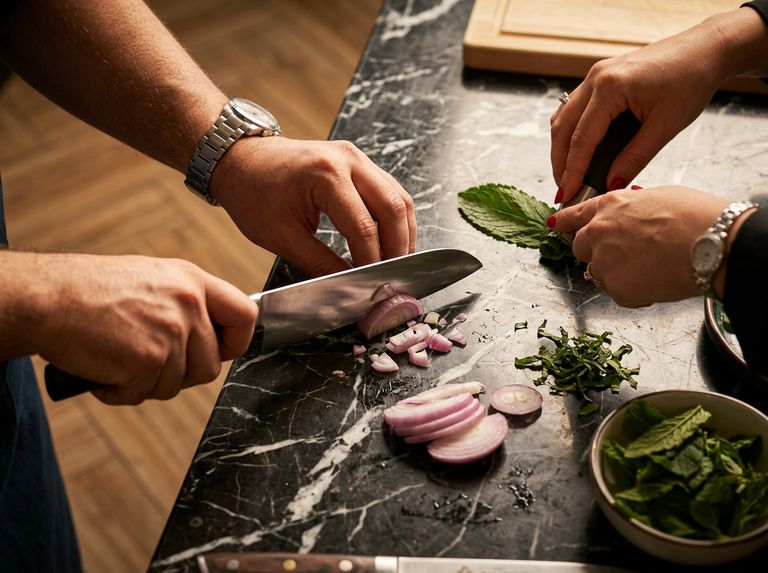 Mains d'un cuisinier débutant maniant un couteau de chef sur une planche en bois — niveau Novice OuiChef Academy